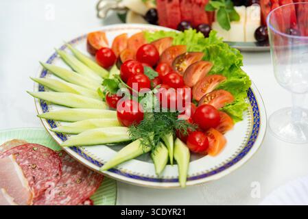 Un assortiment coloré de légumes frais, y compris des concombres, des tomates et de la laitue, disposés sur un plateau. parfait pour les fêtes ou une alimentation saine oc Banque D'Images
