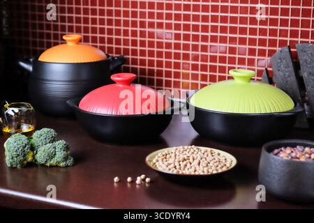 Une gamme vibrante d'ustensiles de cuisine colorés avec des légumes frais affichés sur un comptoir de cuisine Banque D'Images