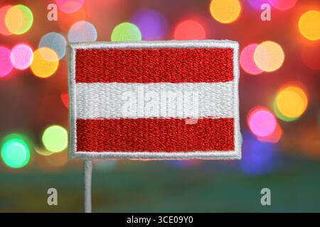 Drapeau autrichien brodé sur un fond de feux d'artifice bokeh étincelant, parfait pour Noël, nouvel an ou les visuels de célébration nationale. Banque D'Images