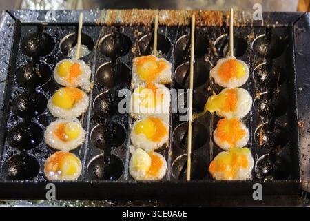 Œufs de caille de rue frits dans de petits moules, brochés et servis dans un marché nocturne thaïlandais, symbolisant le tourisme culinaire authentique de l'Asie du Sud-est. Banque D'Images