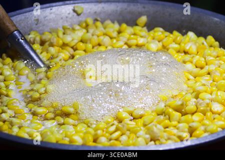 Faire bouillir des grains de maïs sucrés dans un grand pot à vapeur sur un stand de cuisine de rue thaïlandais, mettant en valeur la culture culinaire nocturne authentique dans une atmosphère vibrante. Banque D'Images