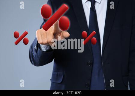 Homme d'affaires touchant le signe de pourcentage virtuel sur fond gris, gros plan Banque D'Images