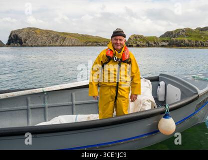 Homme portant irlandais de polissoir jaune et combinaison de pluie gonflant automatique dispositif de flottaison personnel debout dans petit bateau, garnir, Billeragh, Comté Banque D'Images