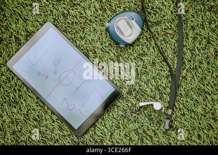 Tablette numérique affichant le diagramme tactique de football reposant sur l'herbe artificielle Banque D'Images