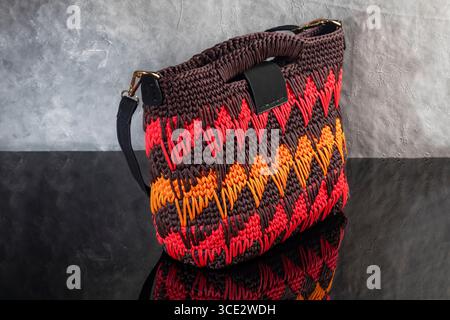 Sac à main pour femmes de couleur marron tricoté à la main avec des tissages orange-rouge et une longue poignée. Fait à la main Banque D'Images
