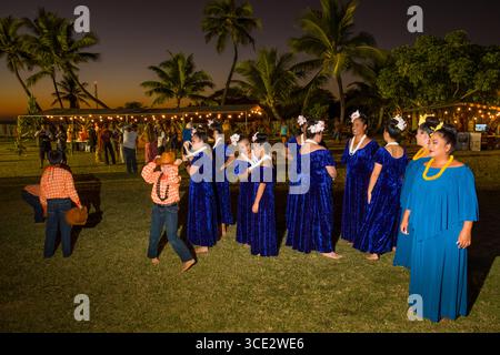 Les femmes portant des robes en velours bleu debout sur pelouse avant leur performance hula, Kekaha Harbour House, Waimea, Kauai, Hawaii, USA Banque D'Images