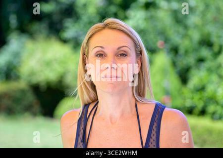 Portrait en gros plan d'une femme blonde calme et confiante dans un débardeur bleu. Banque D'Images