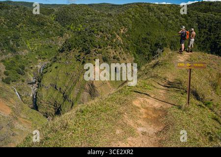 Deux hommes debout à la fin d'un sentier étroit de crête avec vue sur les cascades sur le Waiakoali et les ruisseaux Kauaikinana, Koke'e State Park, Kauai, H. Banque D'Images