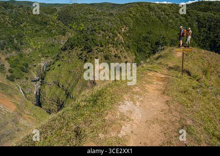 Deux hommes debout à la fin d'un sentier étroit de crête avec vue sur les cascades sur le Waiakoali et les ruisseaux Kauaikinana, Koke'e State Park, Kauai, H. Banque D'Images