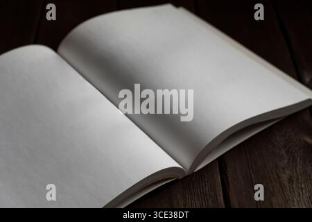 Photo minimaliste d'un livre blanc ouvert sur une surface en bois, idéal pour les maquettes, les modèles, l'écriture ou la lecture de concepts Banque D'Images