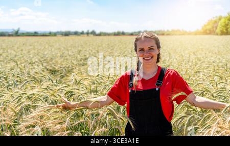 Jeune femelle marchant à travers le champ de céréales vertes dans la saison de croissance dans la campagne Banque D'Images