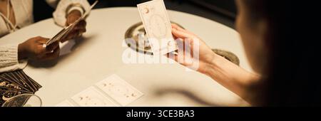 Jeune femme caucasienne lisant des cartes de Tarot avec jeune femme noire à table Banque D'Images