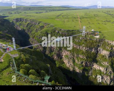 Un long pont avec une plate-forme de verre enjambe une gorge profonde, entouré de paysages verdoyants et de montagnes lointaines, vue aérienne, Diamond Bridge, Diamond Glas Banque D'Images