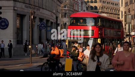 LONDRES, Royaume-Uni - 5 AOÛT 2025 - bus à impériale rouge passant par des piétons et des livreurs dans une rue animée de Londres Banque D'Images