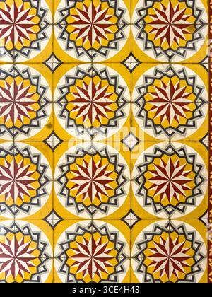 Motif de carreaux géométriques colorés avec des motifs d'étoiles dans des teintes jaunes, rouges et grises créant un design symétrique vibrant. Banque D'Images