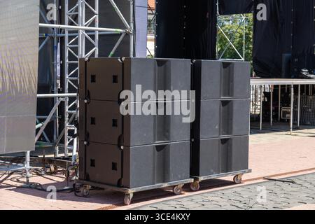 Systèmes acoustiques de concert professionnels installés sur une scène en plein air pour une performance musicale live, prêt pour un spectacle de haute énergie sous le ciel. Banque D'Images