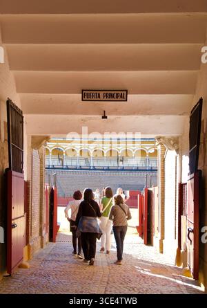 Touristes allant dans la célèbre arène circulaire de Séville du 18ème siècle de 12 000 sièges par la porte principale lors d'une tournée Séville Andalousie Espagne Europe Banque D'Images