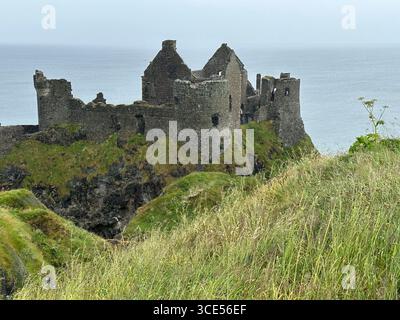 Vagues d'herbe au premier plan d'un plan large du château de Dunluce en Irlande du Nord Banque D'Images