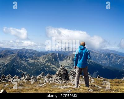 Vue arrière d'un homme adulte moyen debout dans les montagnes volant un drone pour prendre des photos, Bulgarie Banque D'Images