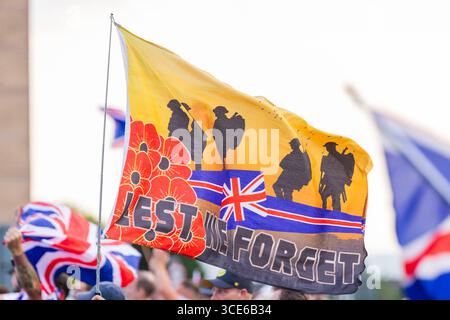 Leeds, Royaume-Uni. 15 AOÛT 2025. Le drapeau "Lest We Forget" pour la quatrième semaine consécutive, des groupes de protestataires pro et anti migrants se sont rassemblés sur le bord de la route près de l'hôtel Britannia à Seacroft, Leeds. Les manifestants de 'Stand Up Leeds' ont déclenché de multiples fusées éclairantes et trois contre-manifestants ont été arrêtés après des échauffourées entre militants et police. Crédit Milo Chandler/Alamy Live News Banque D'Images