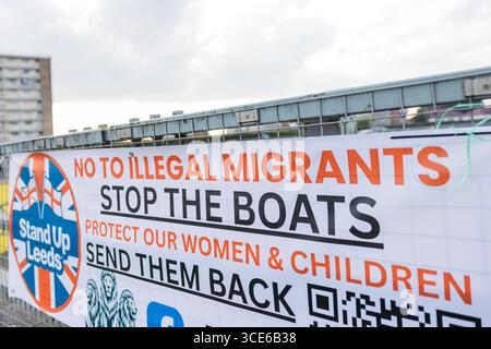 Leeds, Royaume-Uni. 15 AOÛT 2025. La bannière « Stop the Boats » est érigée comme pour la quatrième semaine consécutive, opposant des groupes de manifestants pro et anti-migrants rassemblés sur le bord de la route près de l'hôtel Britannia à Seacroft, Leeds. Les manifestants de 'Stand Up Leeds' ont déclenché de multiples fusées éclairantes et trois contre-manifestants ont été arrêtés après des échauffourées entre militants et police. Crédit Milo Chandler/Alamy Live News Banque D'Images