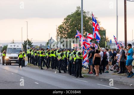Leeds, Royaume-Uni. 15 AOÛT 2025. La police surveille la manifestation « Stand Up Leeds », car pour la quatrième semaine consécutive, des groupes opposés de manifestants pro et anti-migrants se sont rassemblés sur le bord de la route près de l'hôtel Britannia à Seacroft, Leeds. Les manifestants de 'Stand Up Leeds' ont déclenché de multiples fusées éclairantes et trois contre-manifestants ont été arrêtés après des échauffourées entre militants et police. Crédit Milo Chandler/Alamy Live News Banque D'Images