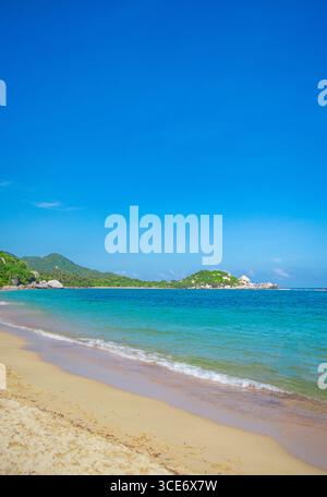 Vue imprenable sur la plage de Cabo San Juan dans le parc national Tayrona, Santa Marta, avec des eaux turquoises et des montagnes luxuriantes. Banque D'Images