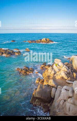 Une vue imprenable sur les formations rocheuses le long de la côte à Tayrona Park, Santa Marta, Colombie, avec des eaux bleues claires sous un ciel lumineux. Banque D'Images