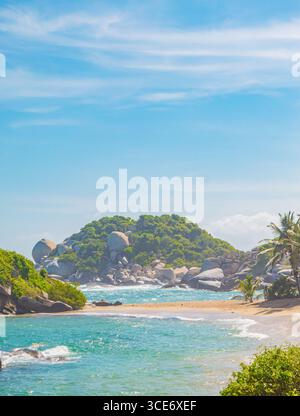 Vue imprenable sur Tayrona Park avec des eaux turquoises, plage de sable et affleurements rocheux sous un ciel bleu clair à Santa Marta, en Colombie. Banque D'Images