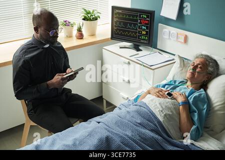 Aumônier fournissant un soutien spirituel à la femme aînée à l'hôpital Banque D'Images
