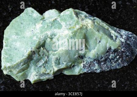 Échantillon de minéral de jade teyskiy brut sur fond de granit noir gros plan du gisement de Teyskoe, Khakassia, Russie Banque D'Images