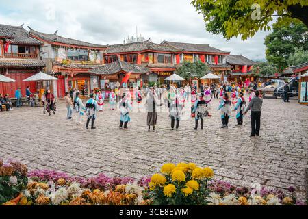 Lijiang, Chine - 24 octobre 2024 : des artistes locaux en robe traditionnelle colorée dansant sur la place de la vieille ville de Lijiang, Yunnan, Chine. Banque D'Images