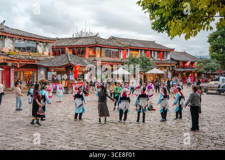 Lijiang, Chine - 24 octobre 2024 : des artistes locaux en robe traditionnelle colorée dansant sur la place de la vieille ville de Lijiang, Yunnan, Chine. Banque D'Images