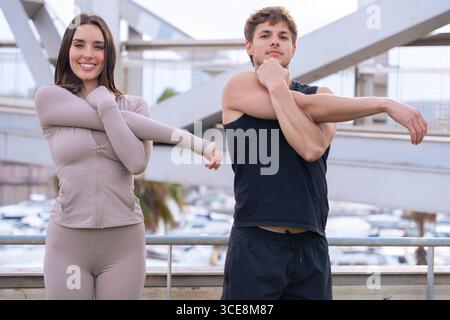 Ajustez couple en étirant les bras à l'extérieur avant l'entraînement sur le pont urbain Banque D'Images