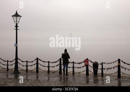 Femme debout contre la rampe sur Liverpool Waterfront dans Fog, Albert Dock Banque D'Images