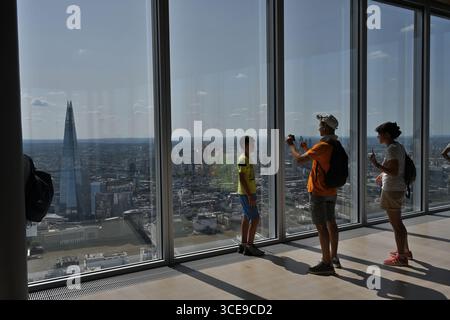 Un garçon pose pour une photographie de sa famille devant le Shard vu depuis la plate-forme d'observation Lookout au 8 Bishopsgate - Londres Royaume-Uni Banque D'Images