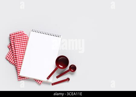 Composition avec livre de recettes vierge, ustensiles de cuisine et serviette sur fond gris Banque D'Images