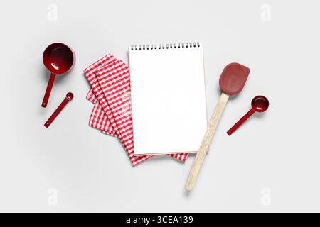 Composition avec livre de recettes vierge, ustensiles de cuisine et serviette sur fond gris Banque D'Images