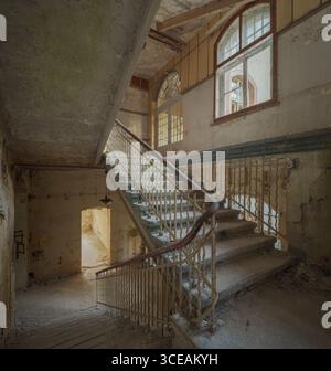 Intérieur de bâtiment historique abandonné avec arche en pierre, escalier et lumière naturelle à travers des portes ouvertes, architecture ancienne, Europe. Banque D'Images