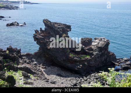 Une vue rapprochée de Yongduam, ou Dragon Head Rock, montre la formation de lave érodée dépassant de la côte rocheuse au-dessus de l'eau bleu clair sur le sho nord de Jeju Banque D'Images