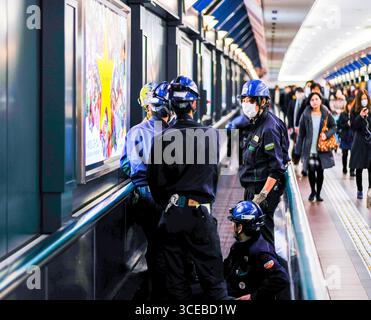 Les hommes portant des casques de travailler sur tapis roulant qui relie la station Ebisu Ebisu Garden Place, à Shibuya, Tokyo, Honshu, Japan Banque D'Images