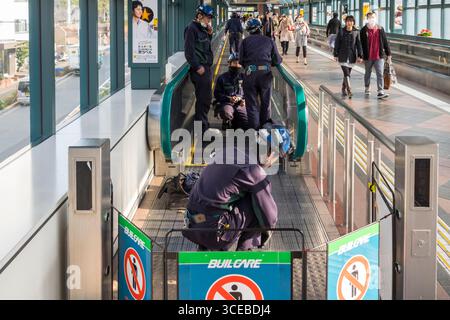 Les hommes portant des casques de travailler sur tapis roulant qui relie la station Ebisu Ebisu Garden Place, à Shibuya, Tokyo, Honshu, Japan Banque D'Images