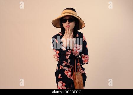 femme élégante en robe florale portant chapeau et lunettes de soleil Banque D'Images