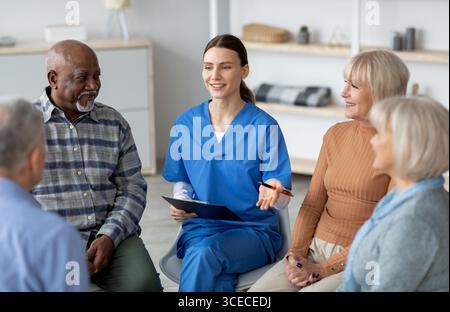 Jeune femme sympathique psychologue ayant une conversation avec des personnes âgées Banque D'Images
