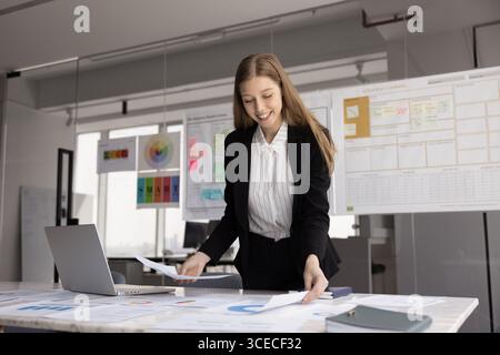 Positive satisfaite jeune femme professionnelle vérifiant les données de marketing Banque D'Images