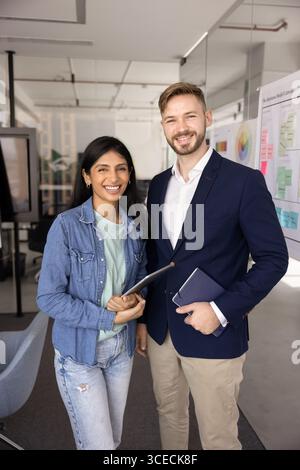 Deux jeunes collègues d'affaires multiethniques heureux posant pour un portrait d'affaires Banque D'Images