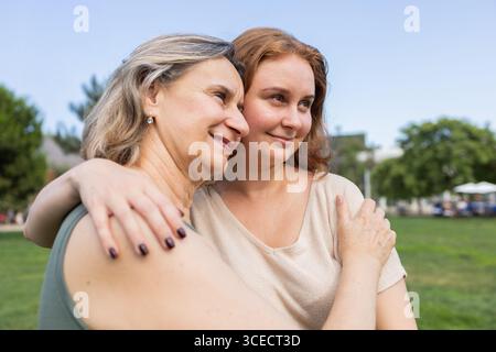 Une image réconfortante d'une mère et d'une fille embrassant affectueusement dans un environnement de parc serein, mettant en valeur l'amour, la connexion et la beauté de fa Banque D'Images