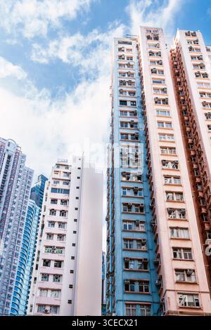 Les grands bâtiments résidentiels dominent le paysage urbain de Hong Kong, mettant en valeur l'architecture vibrante et la densité urbaine sur fond de ciel bleu clair et Banque D'Images