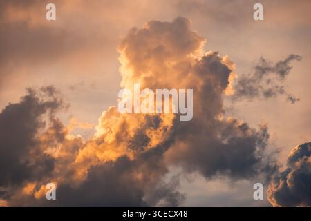 Une vue captivante de nuages spectaculaires illuminés par les teintes vibrantes d'un soleil couchant, créant un contraste saisissant avec un ciel silencieux, évoquant une se Banque D'Images