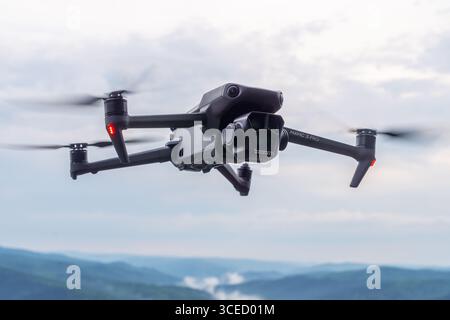 Drone capture une vue aérienne époustouflante du paysage montagneux tout en survolant des vallées luxuriantes et des sommets brumeux pendant l'heure dorée Banque D'Images
